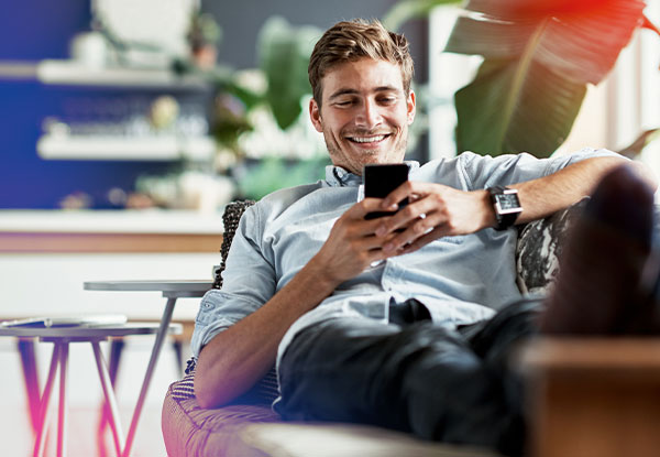 Mann mit Handy auf dem Sofa
