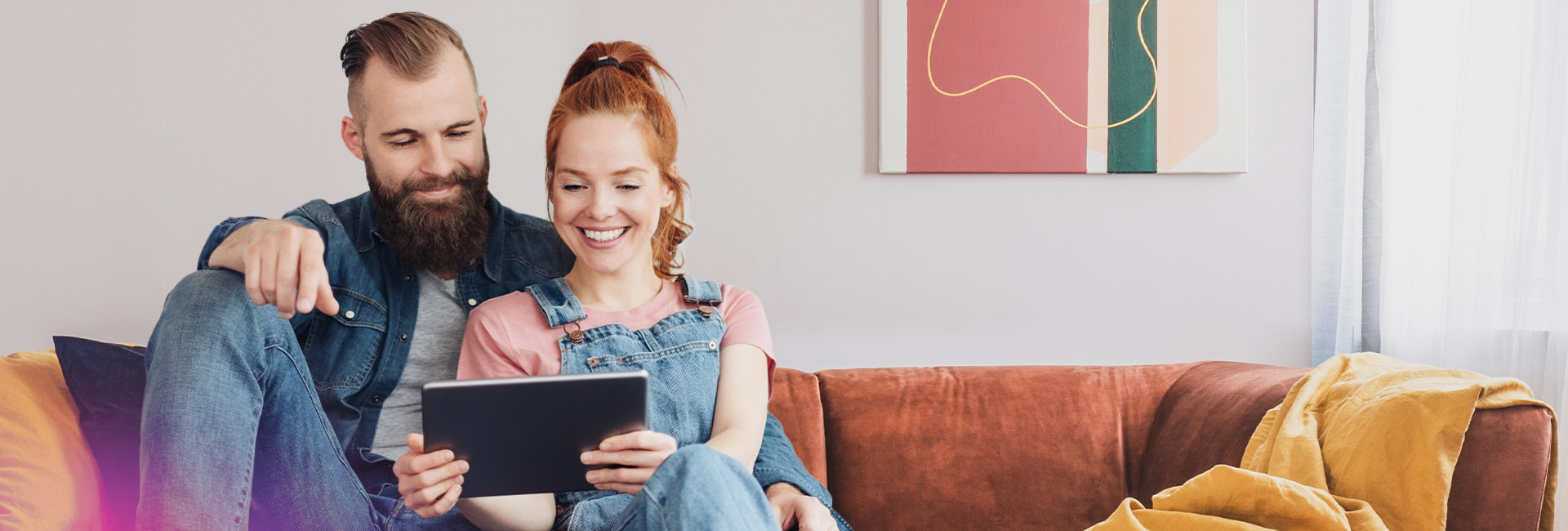 Junges Paar mit Tablet sitzt auf dem Sofa